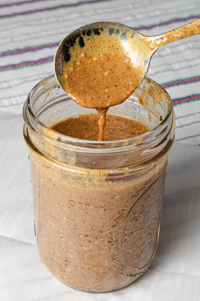 Spooning tangy lowcountry style South Carolina gold mustard BBQ sauce into a jar.