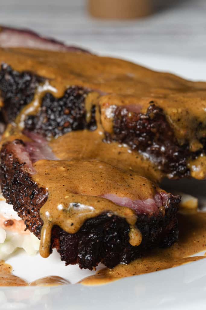 A plate of smoked brisket covered in Carolina gold mustard sauce.