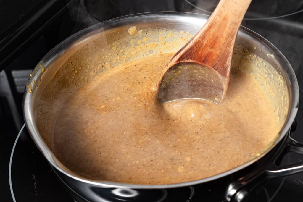 Stirring a pot of simmering Carolina gold mustard BBQ sauce.