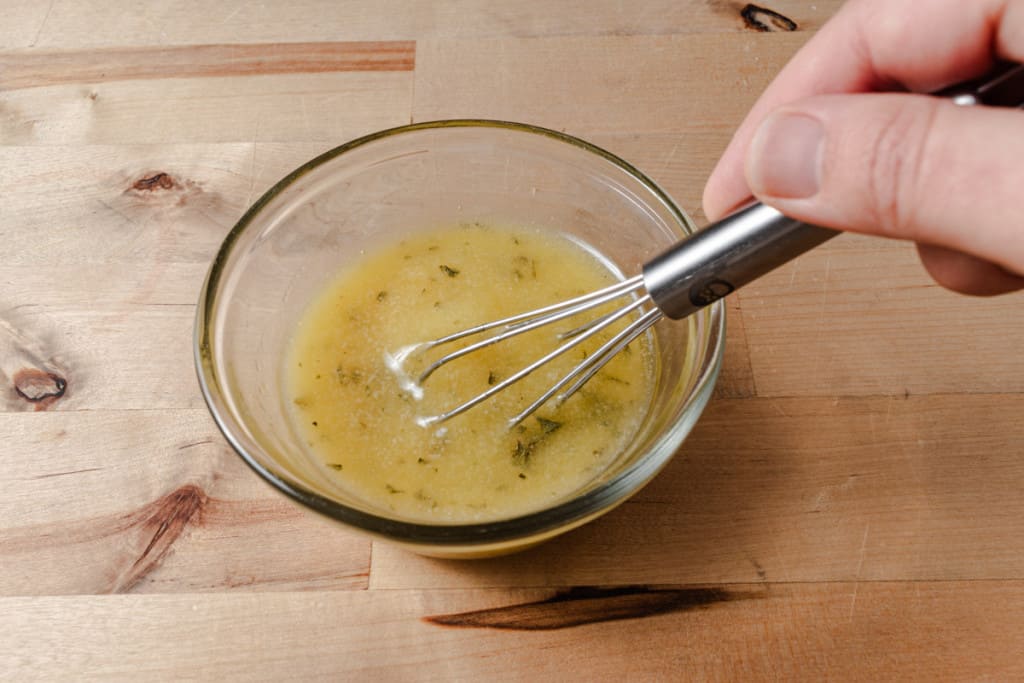 Stirring garlic herb mix into melted butter.