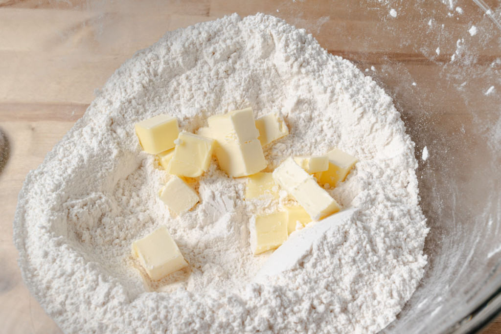 Adding cubes of cold butter to a flour mixture.