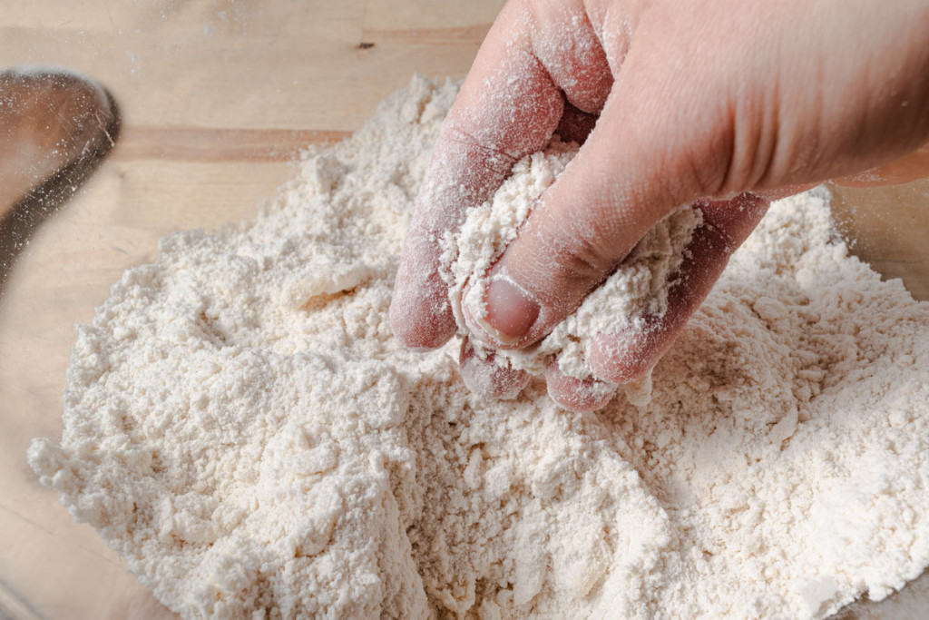 Using hands to cut butter into flour.