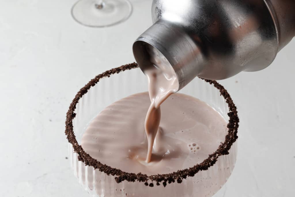 Pouring a chocolate martini into a chocolate rimmed coupe martini glass.