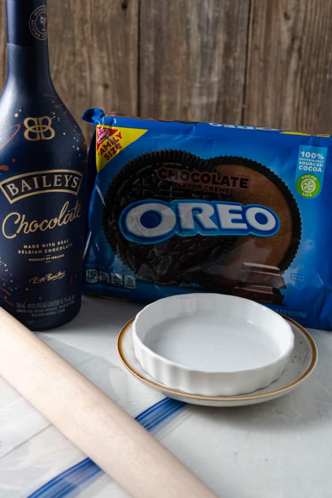 Oreos, chocolate liqueur, shallow dishes, a rolling pin, and a plastic bag for making a fancy chocolate rim on a martini glass.