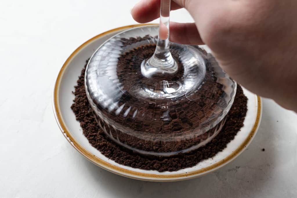 Dipping a coupe martini glass rim in chocolate cookie crumbs.