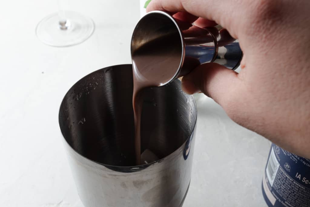 Pouring chocolate liqueur into a cocktail shaker.