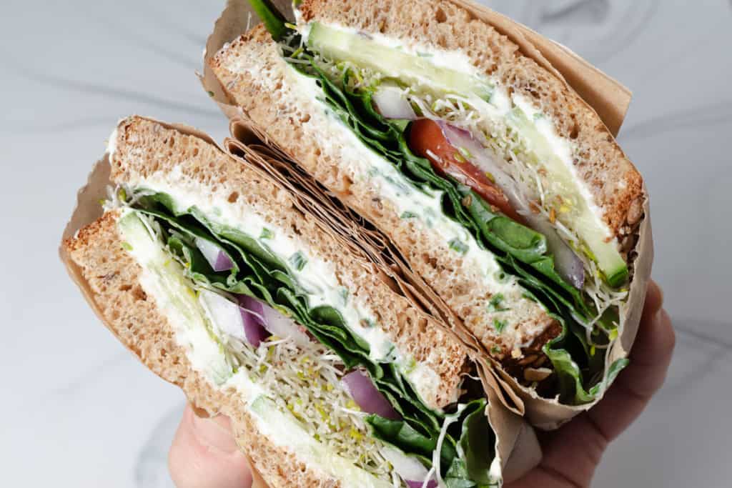 A hearty veggie and cream cheese sandwich cross section.