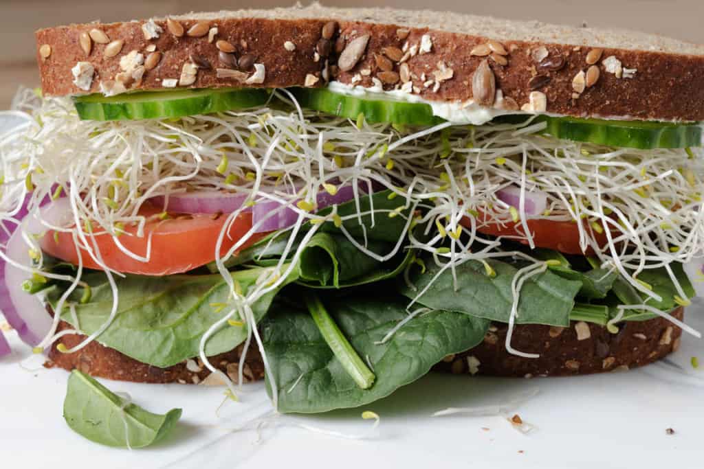 A loaded cream cheese and vegetable sandwich on hearty whole grain sandwich bread.