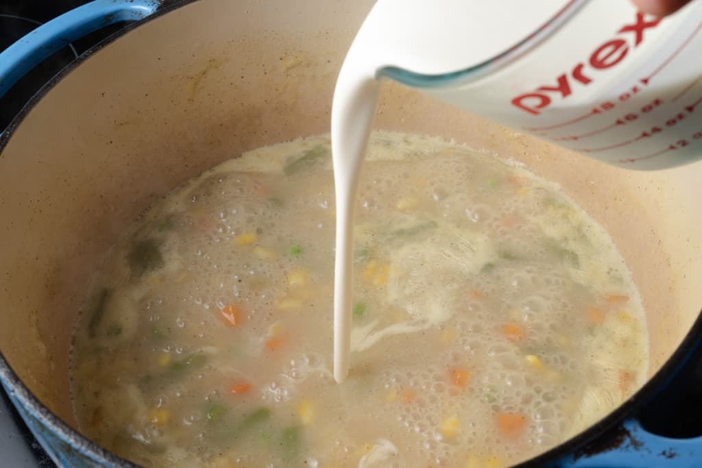 Pouring cream into a pot of Dixie Stampede style soup.