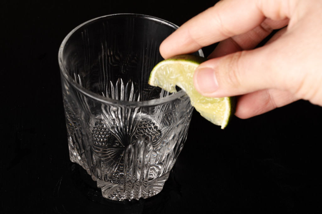 Rimming a rocks glass with lime.