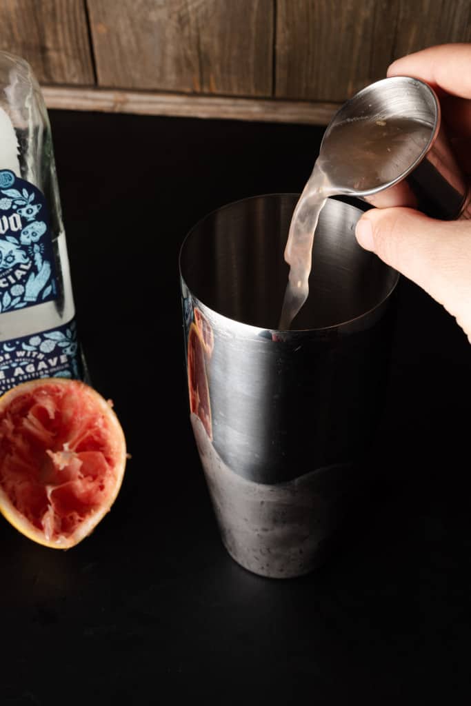 Pouring grapefruit juice in a cocktail shaker.