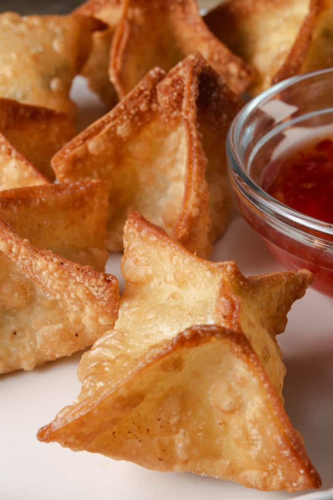A plate of jalapeno popper wontons with sweet chili sauce.