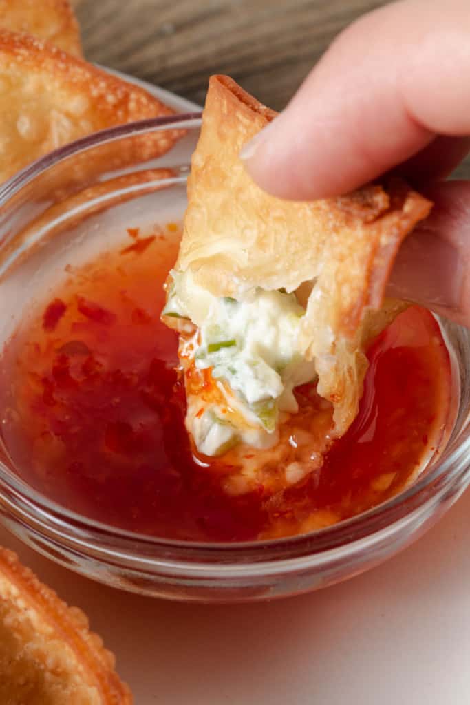 Dipping a jalapeno popper wonton in sweet chili sauce.