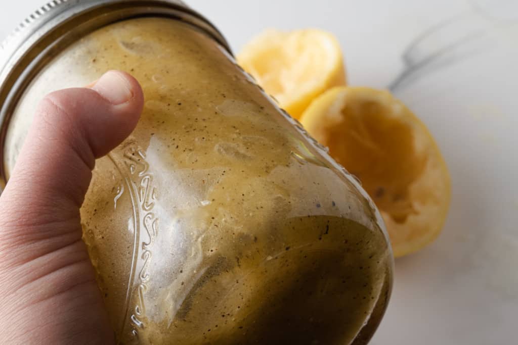 Shaking a jar of lemon vinaigrette.