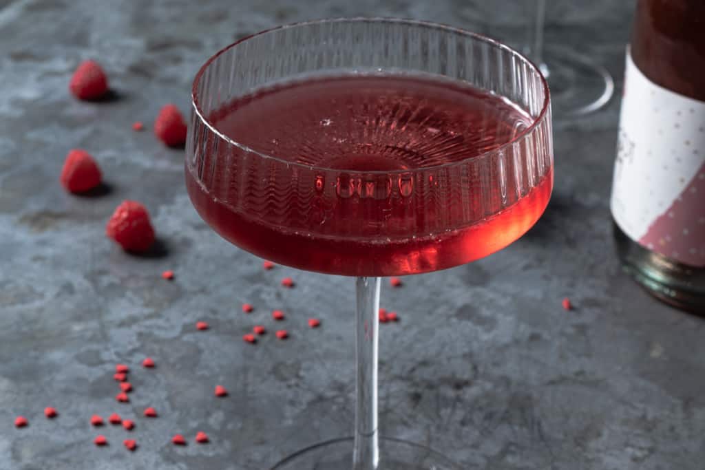 Chilled raspberry liqueur, raspberry vodka, and simple syrup in a coupe glass to make a Valentine's cocktail drink.