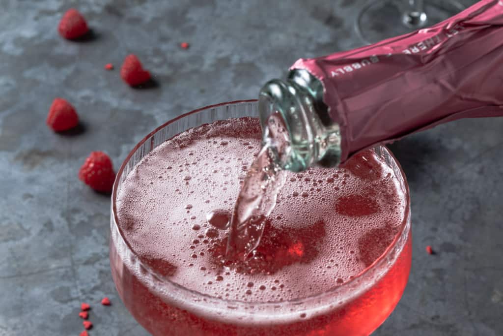 Pouring pink champagne into a love potion cocktail.