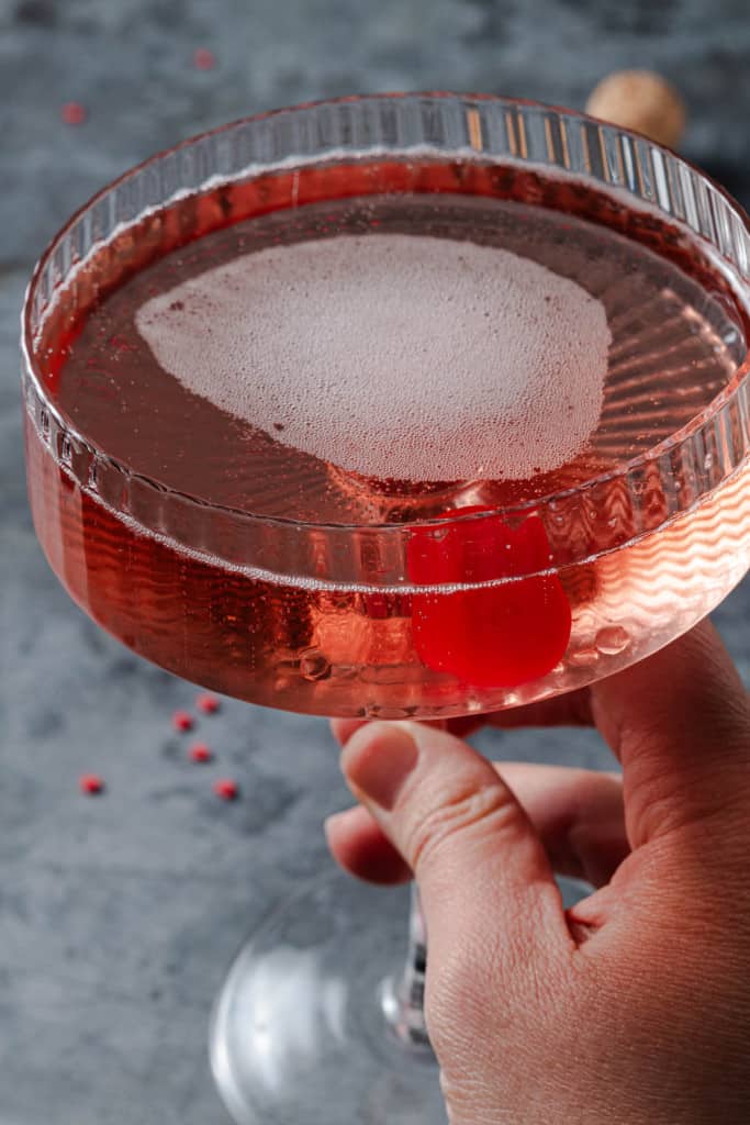 Holding a pink champagne cocktail.