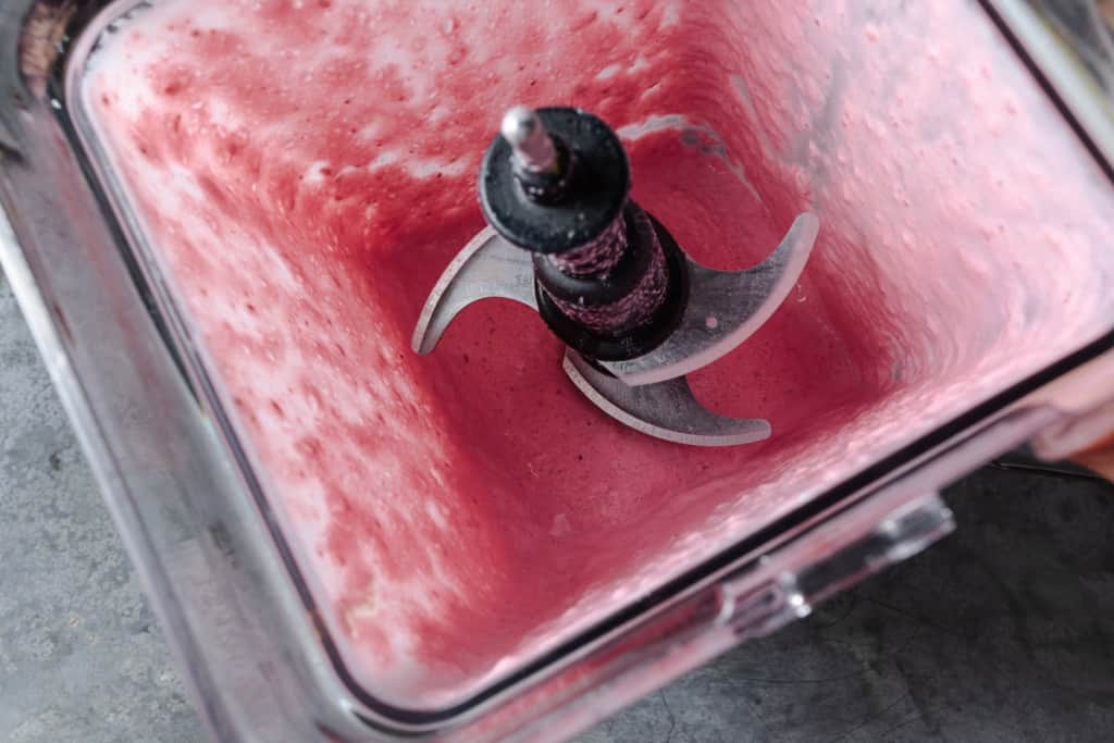 A pink smoothie in a blender.