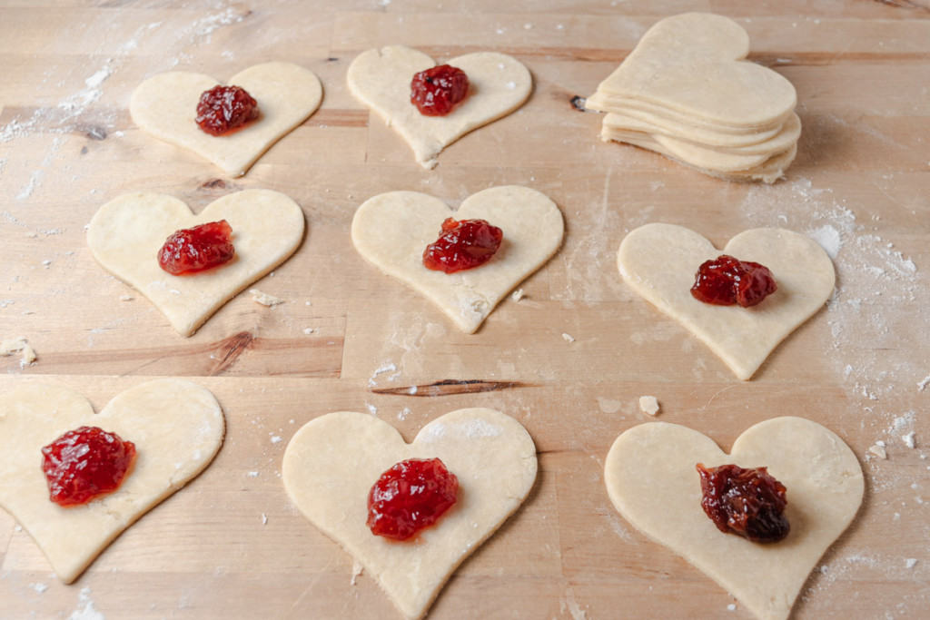 Heart-shaped pie dough cutouts with strawberry jam in the center.