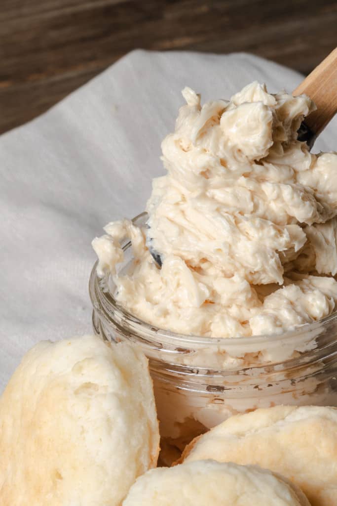 A jar of whipped honey butter with biscuits.