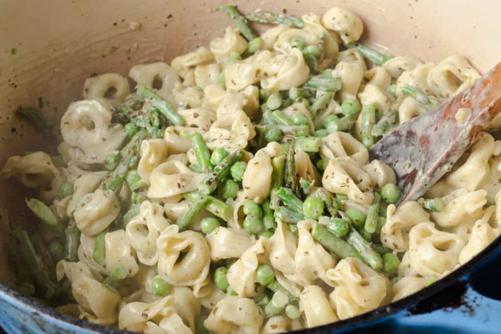 Stirring pesto tortellini with spring vegetables.