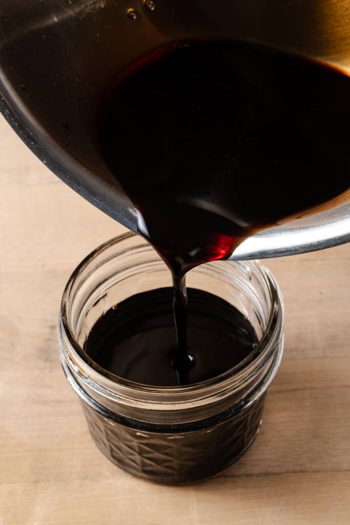 Pouring balsamic glaze into a jar.