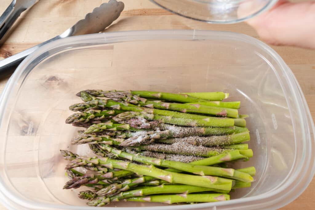 Seasoning asparagus with salt and pepper.