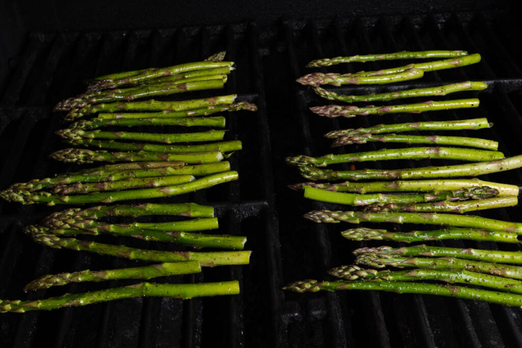 Asparagus stalks cooking on a grill.