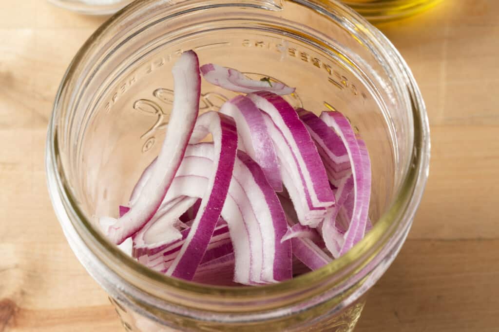 Sliced red onions in a mason jar.