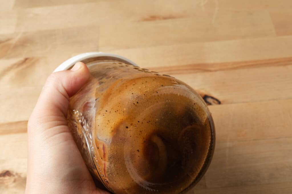 Shaking balsamic dressing in a jar.