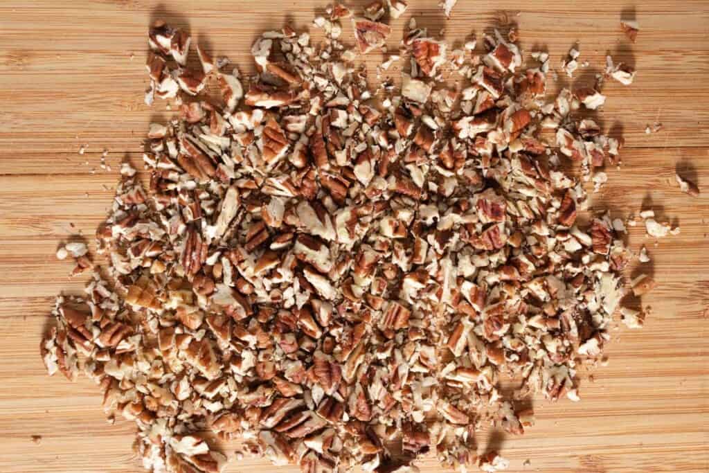 Chopping toasted pecans on a cutting board.