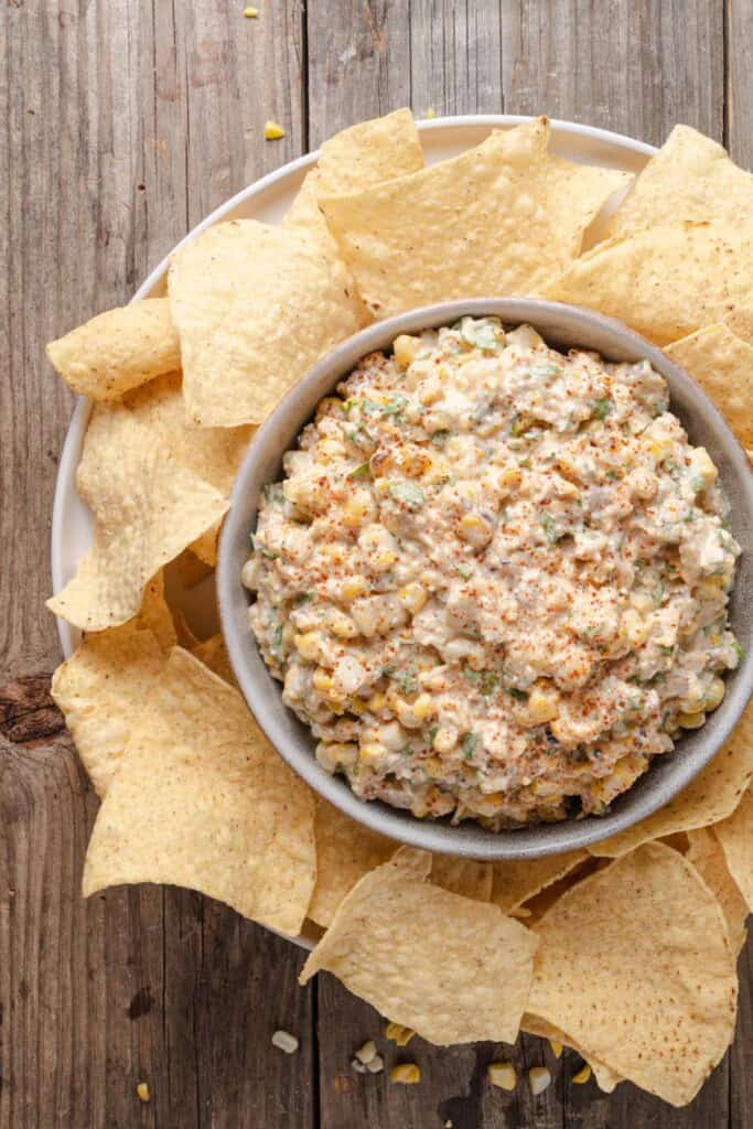 A bowl of Mexican street corn dip with tortilla chips.