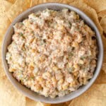 A bowl of Mexican street corn dip with tortilla chips.