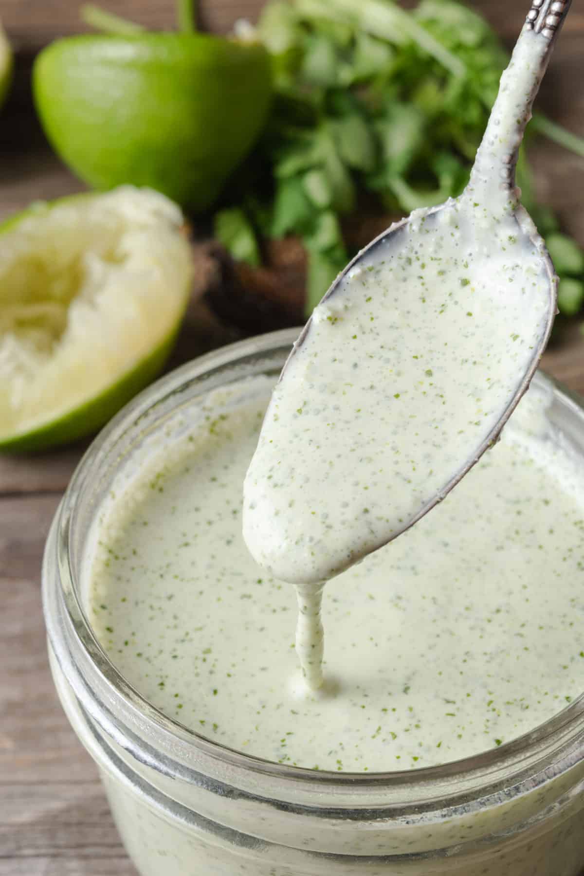 Spooning homemade cilantro lime crema into a jar.