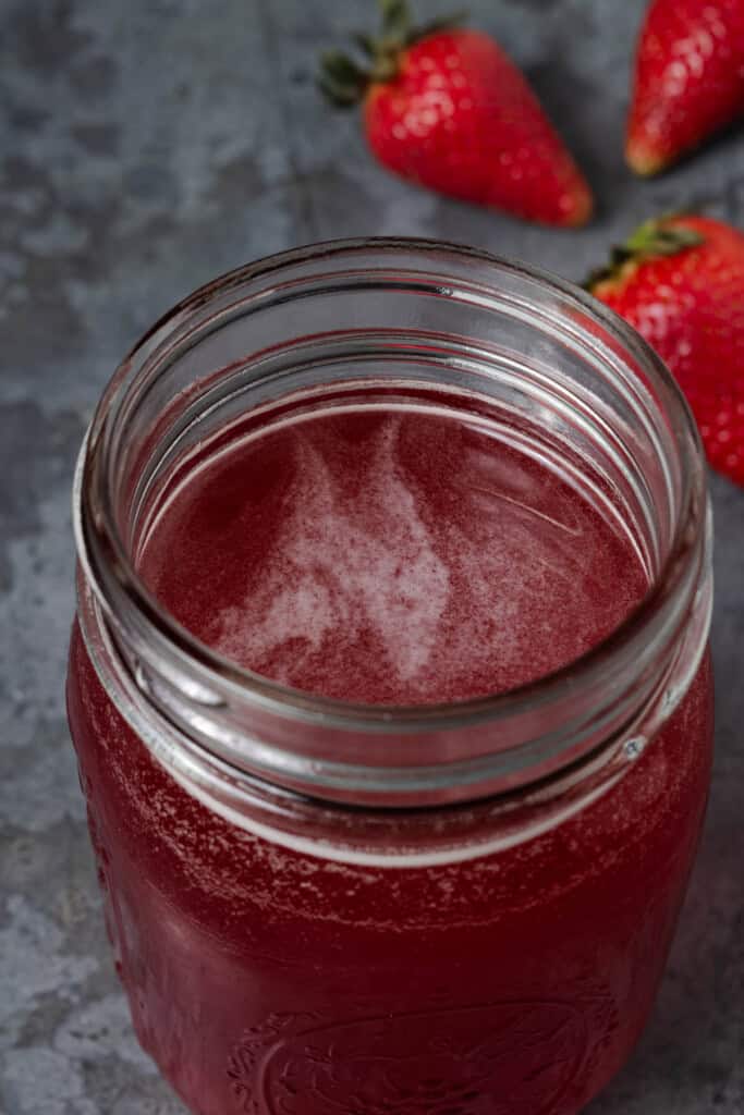 A jar of homemade strawberry simple syrup.