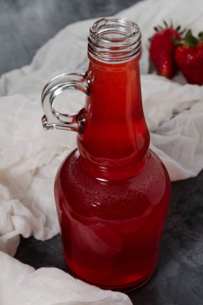 A small jug of strawberry simple syrup for cocktails.