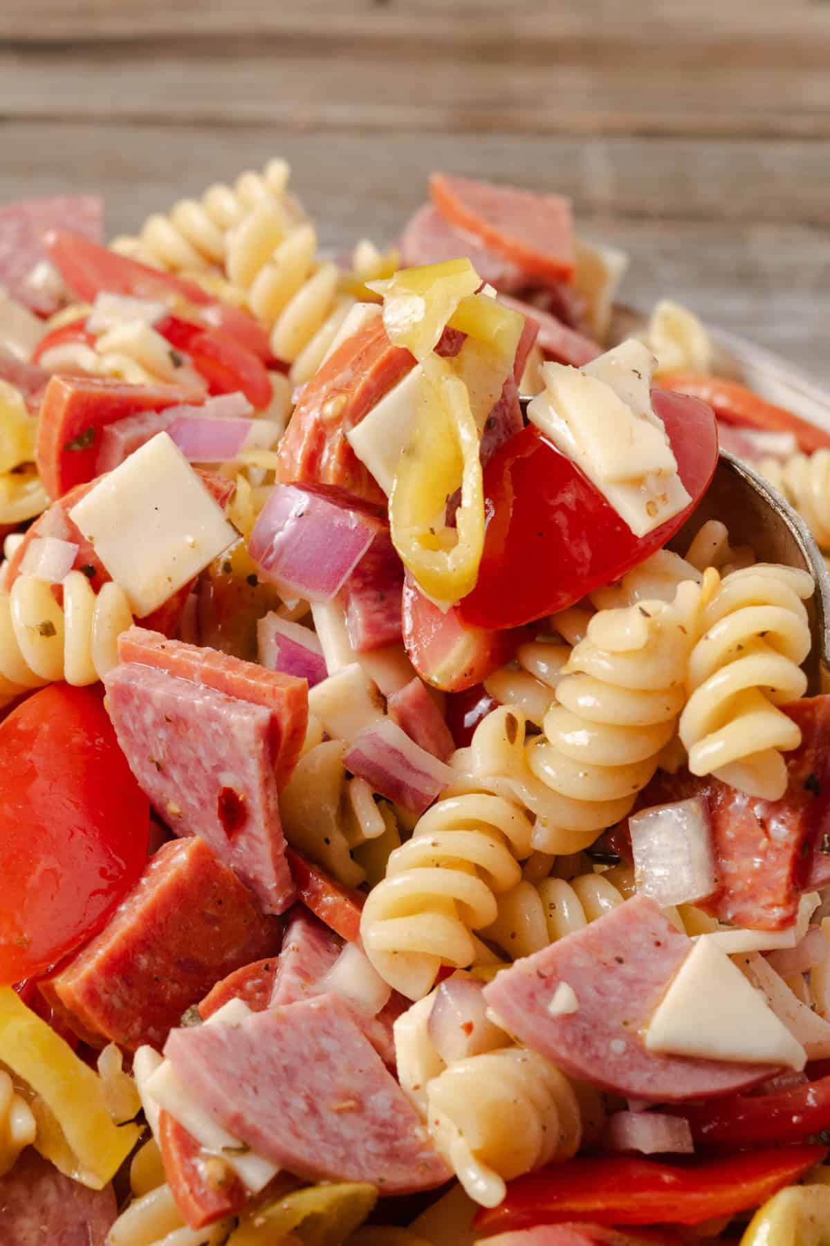 Italian sub pasta salad with salami, pepperoni, tomatoes, onions, and pepperoncini peppers.