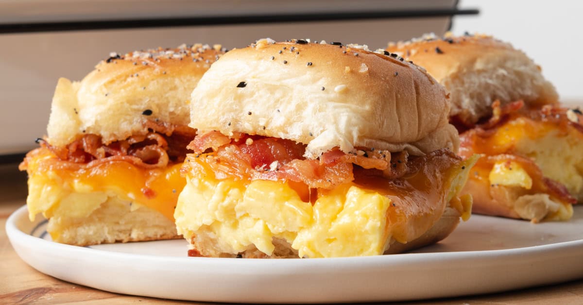 A plate of bacon, egg, and cheese breakfast sliders on sweet Hawaiian rolls.