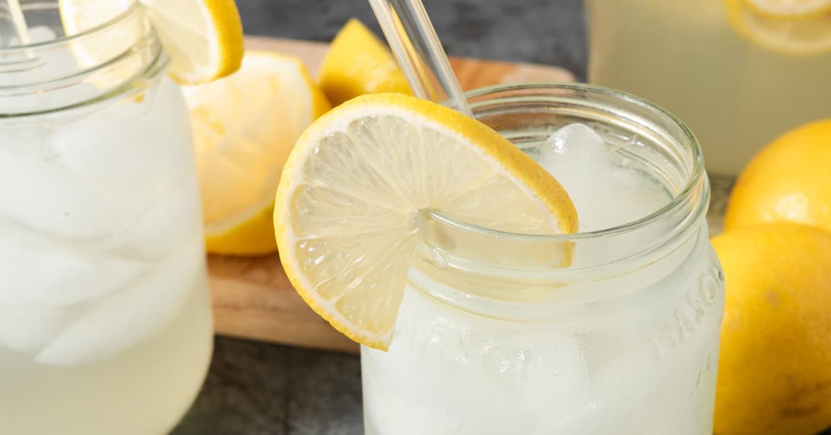 A jar of fresh squeezed homemade lemonade with a lemon garnish.