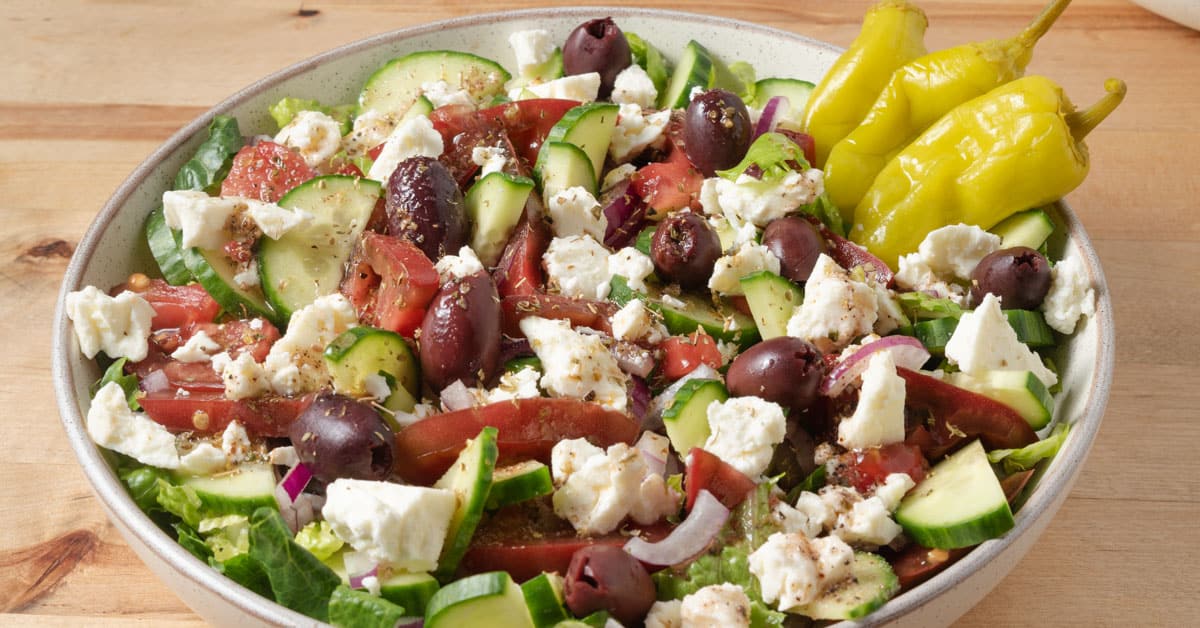 An American style Greek salad with lettuce, cucumbers, tomatoes, red onions, olives, and feta.