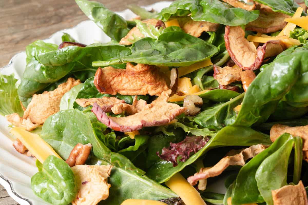 A harvest apple salad with mixed greens with apple dijon vinaigrette, shredded cheddar, and chopped pecans.
