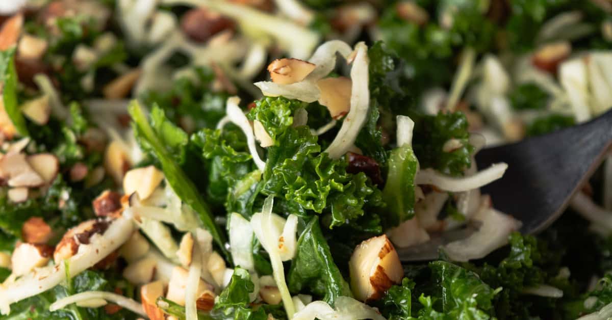 Scooping up a bite of homemade kale, cabbage, and almond salad with a fork.