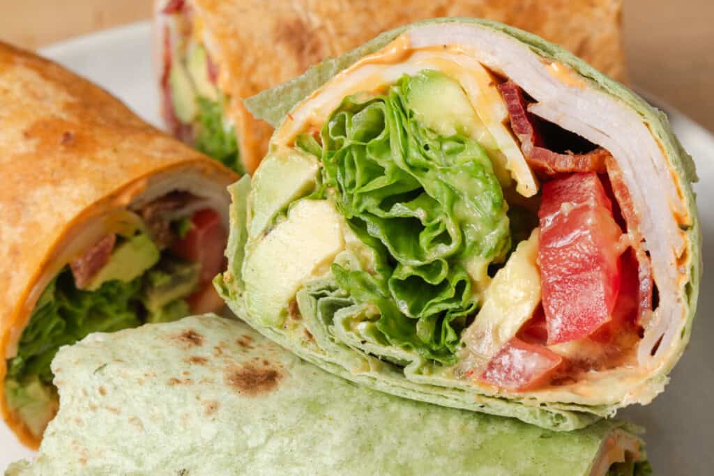 Turkey wraps cut in half and piled on a plate.