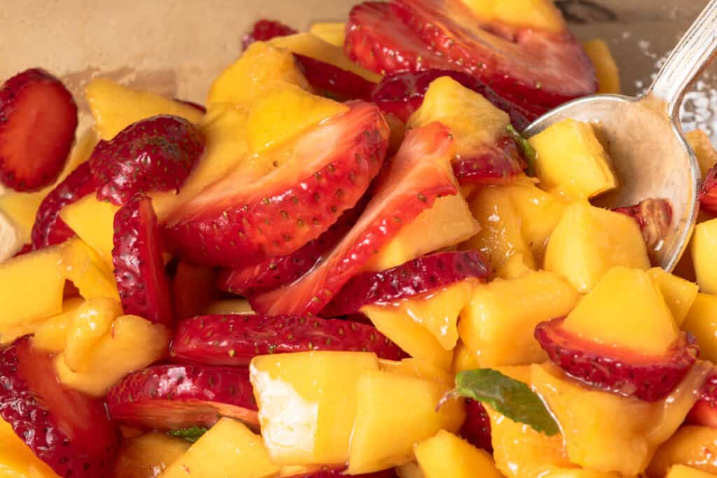 Strawberries, mango, honey, and lime in a bowl.