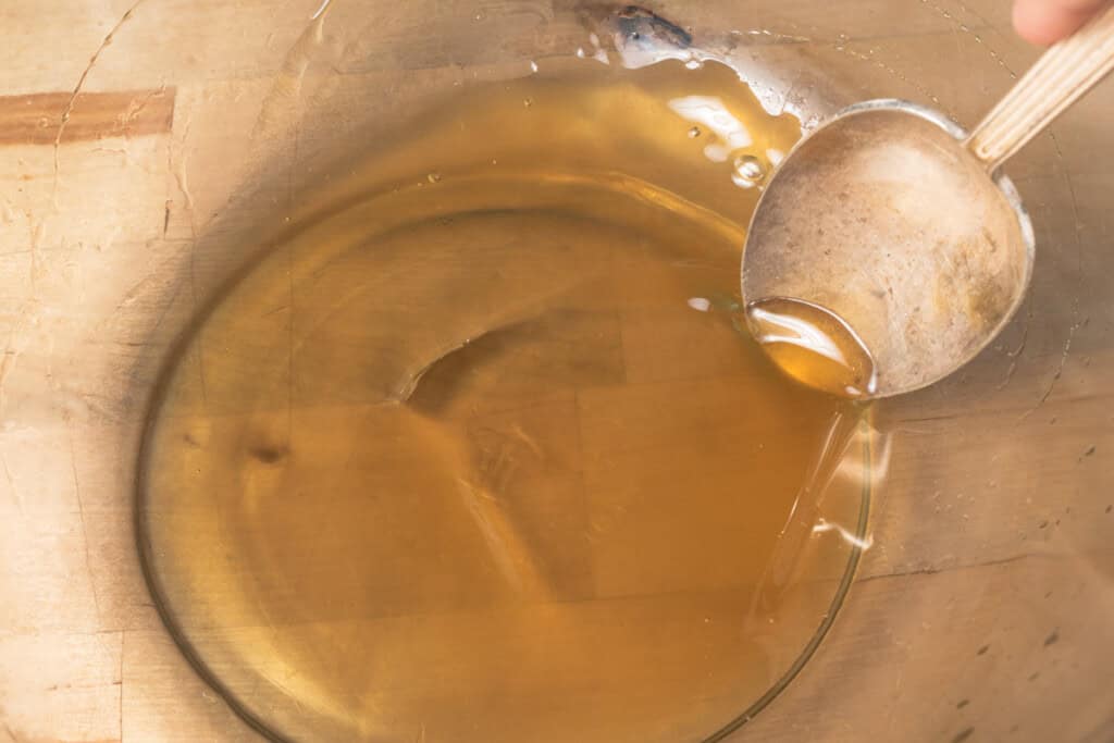 A spoon being used to stir honey and lime juice into a bowl.