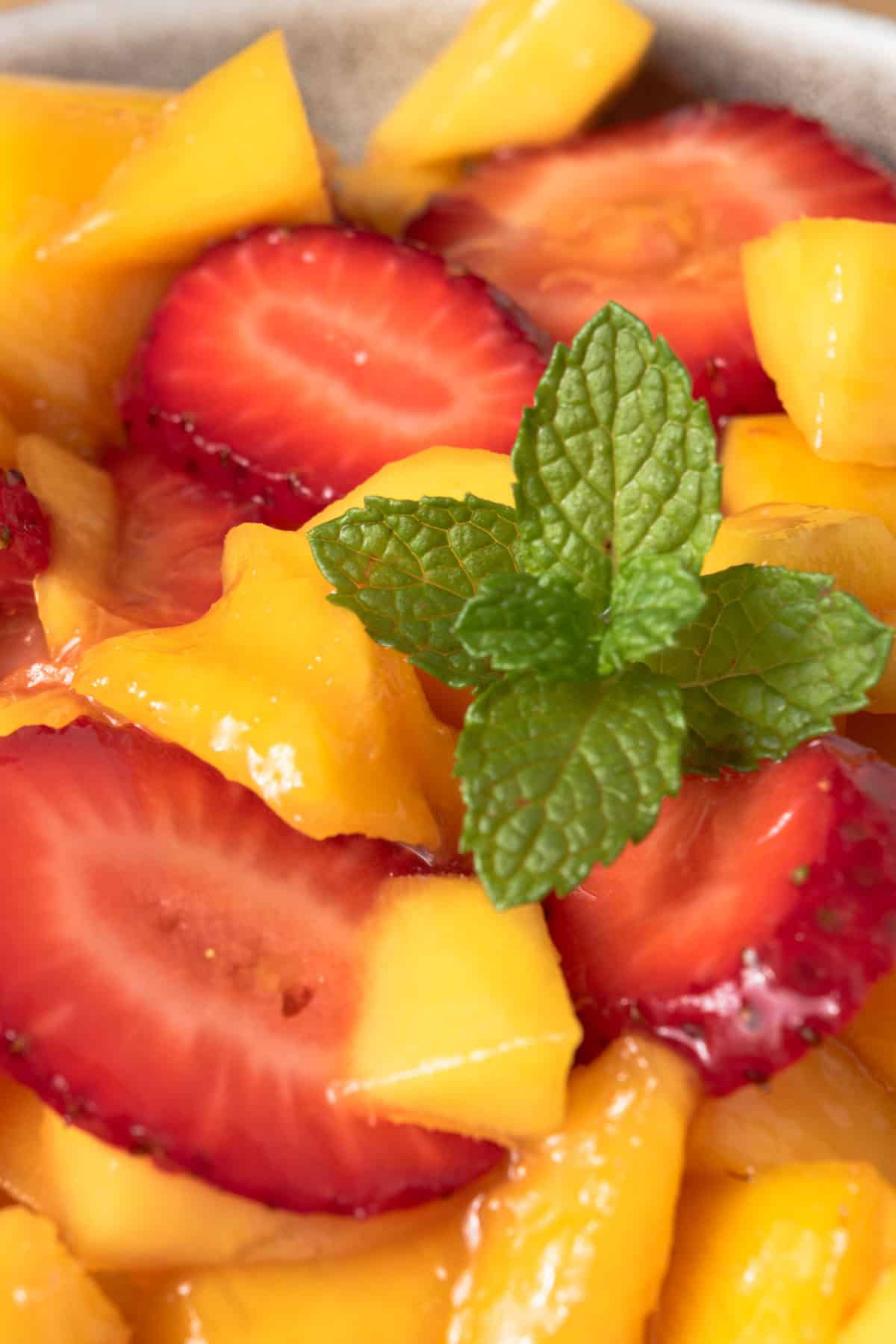 Homemade strawberry mango salad garnished with mint.