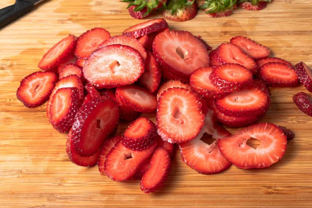 Sliced strawberries on a cutting board.