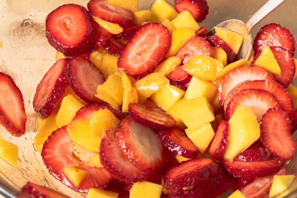 Strawberries, mango, honey, and lime in a bowl.