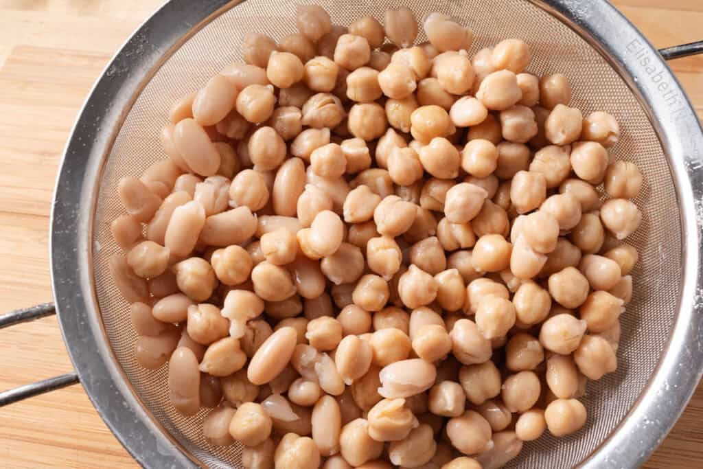 Chickpeas and cannellini beans in a mesh strainer.