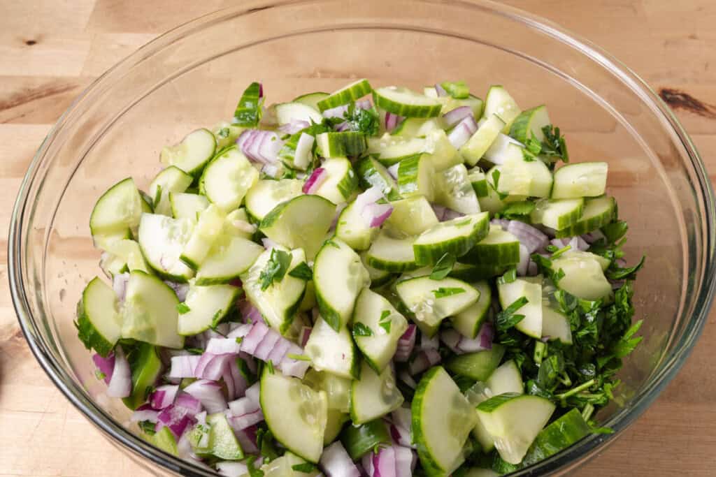 A bowl of chopped vegetables, beans, and dressing.